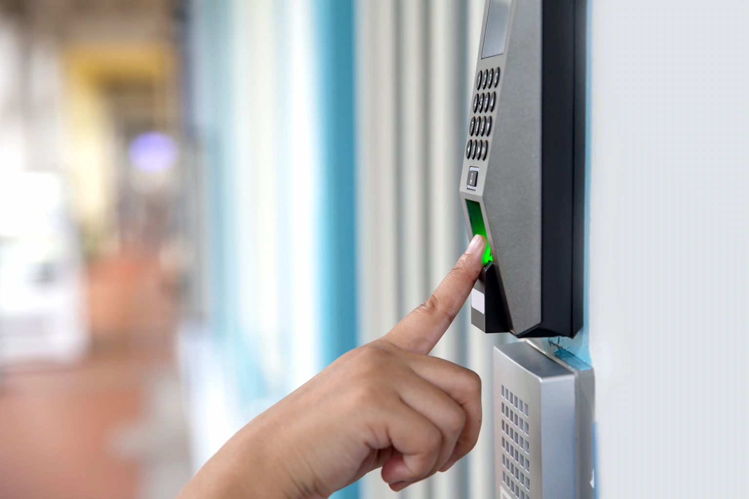 Person using fingerprint scanner on a commercial access control keypad for secure building entry